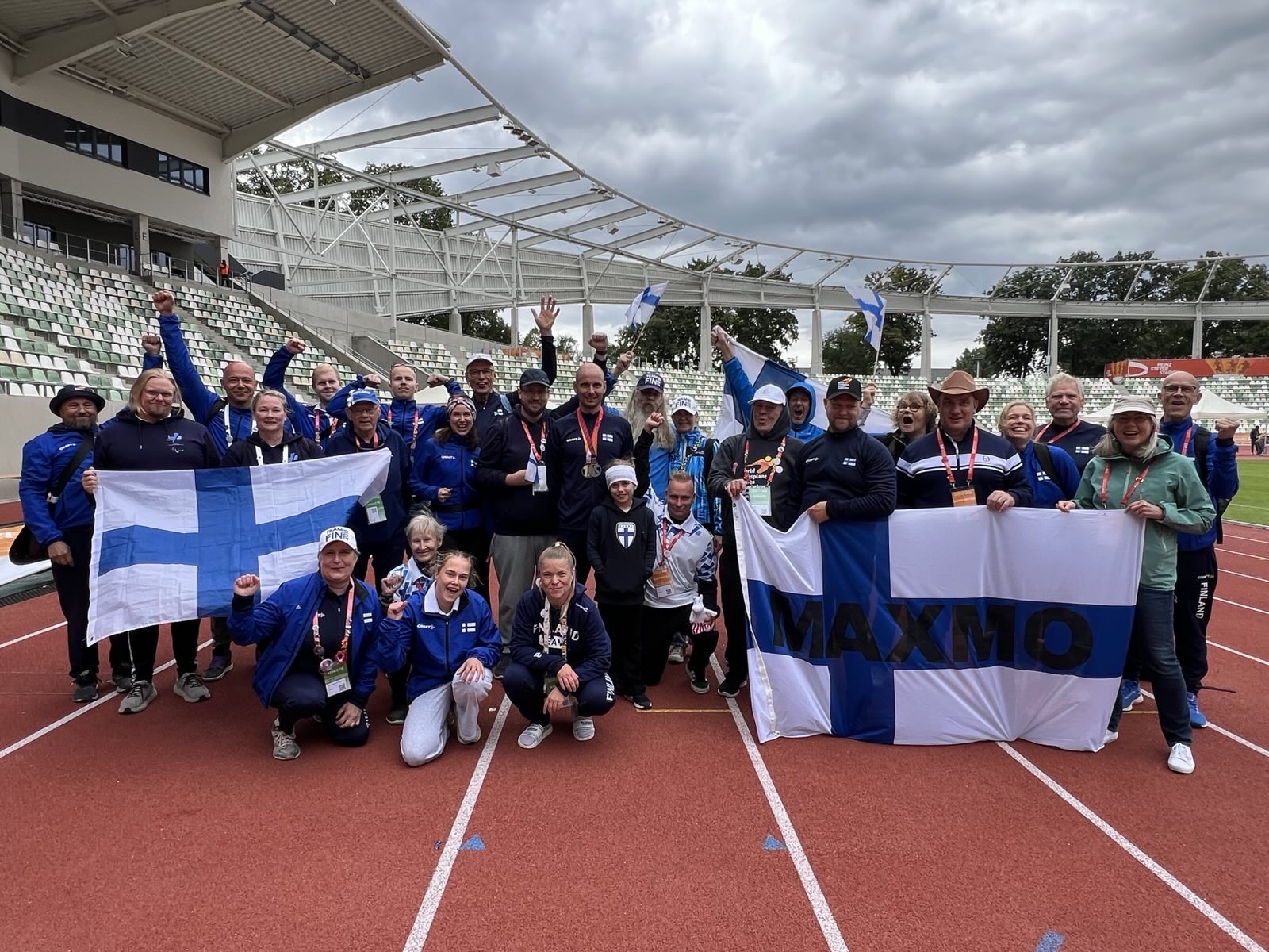 Suomen MM-joukkue tuulettaa lippujen kanssa yhteiskuvassa pilvisellä Dresdenin yleisurheilustadionilla kisojen päätöspäivänä.